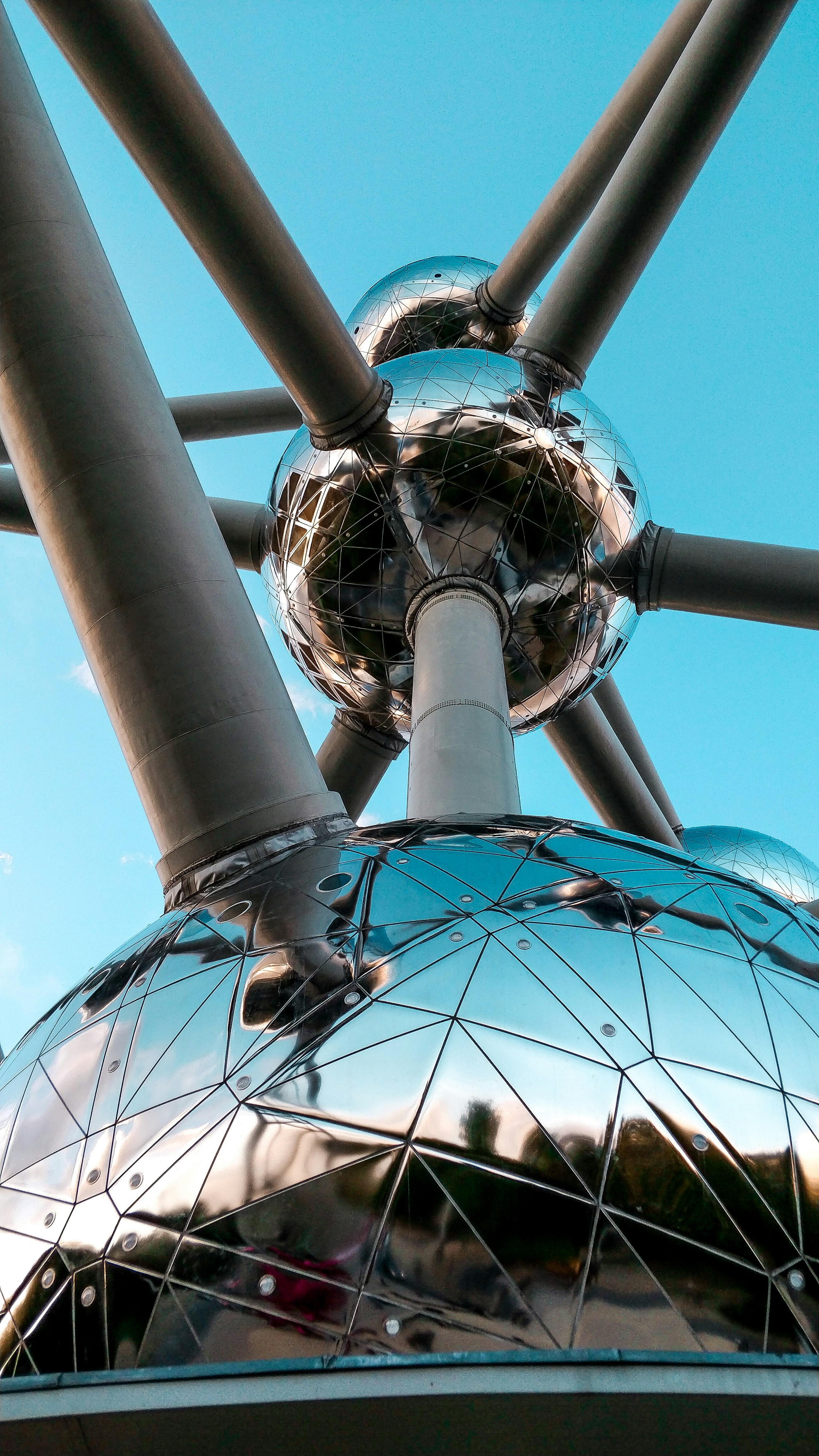 silver-colored spherical structure with attached gray pipes under blue sky